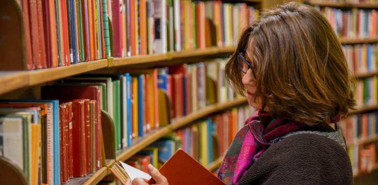 De nouveaux noms pour les bibliothèques grenobloises : dame consultant un livre dans une bibliothèque